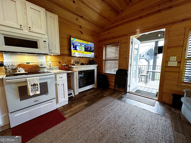 kitchen with white appliances, dark wood-type flooring, white cabinetry, wood walls, and lofted ceiling