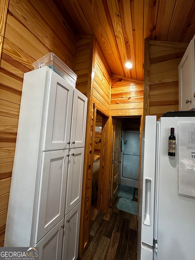 kitchen with white cabinets, lofted ceiling, wooden walls, white fridge with ice dispenser, and dark hardwood / wood-style flooring