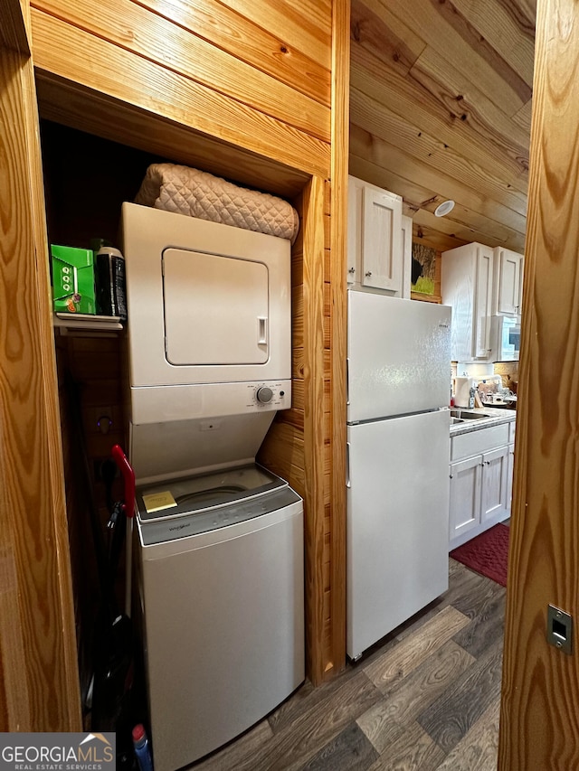 washroom with wooden walls, dark wood-type flooring, and stacked washing maching and dryer