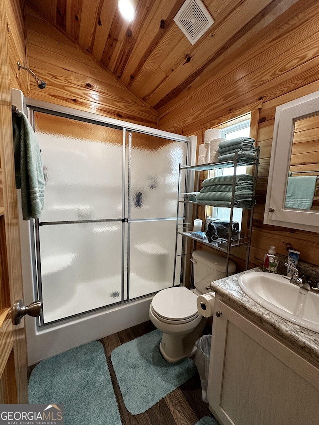 bathroom featuring vanity, lofted ceiling, wooden walls, toilet, and an enclosed shower