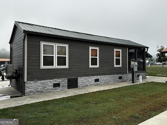 view of side of property with crawl space, a yard, and metal roof