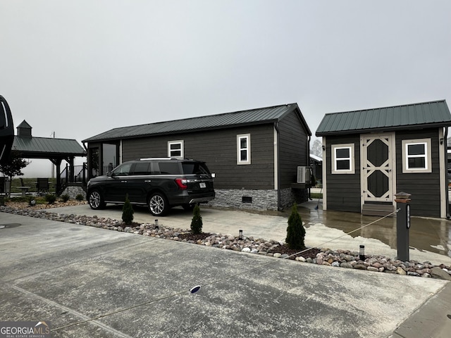 view of property exterior with metal roof, crawl space, and an outbuilding