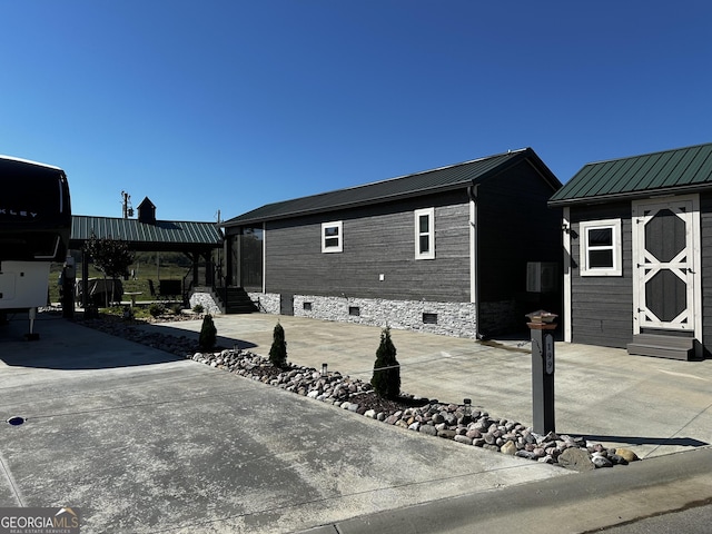 view of side of property with entry steps, metal roof, and crawl space
