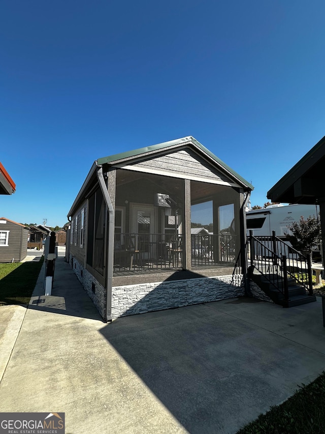 rear view of property with a sunroom and a patio area