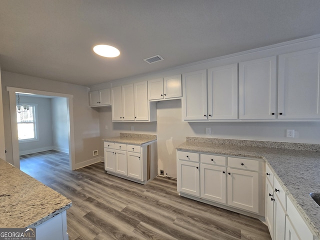 kitchen featuring white cabinetry, hardwood / wood-style floors, and light stone countertops