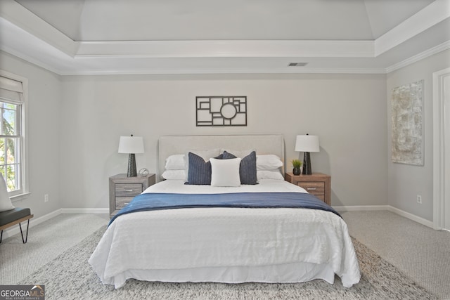 carpeted bedroom with ornamental molding and a tray ceiling