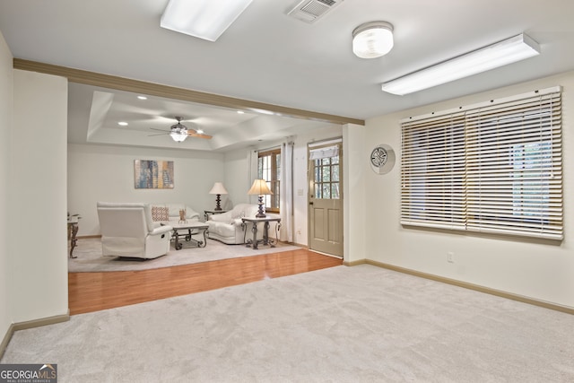 unfurnished living room with a healthy amount of sunlight, a tray ceiling, ceiling fan, and wood-type flooring