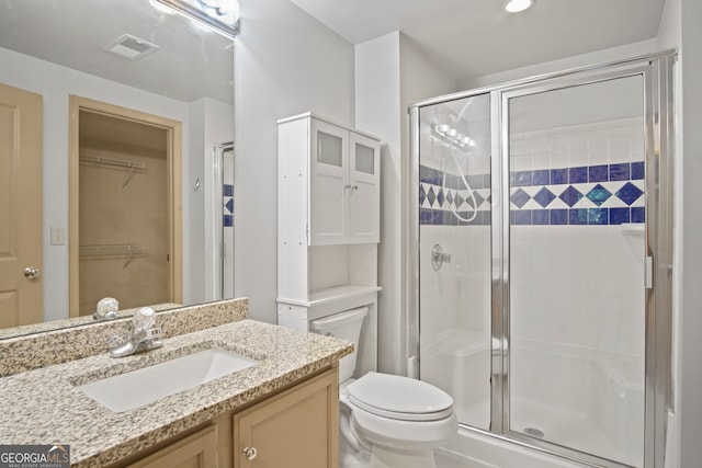 bathroom with vanity, toilet, and a shower with door