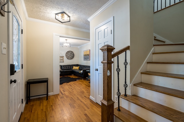 foyer with a textured ceiling, ornamental molding, and hardwood / wood-style flooring