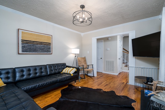 living room featuring an inviting chandelier, wood-type flooring, a textured ceiling, and crown molding