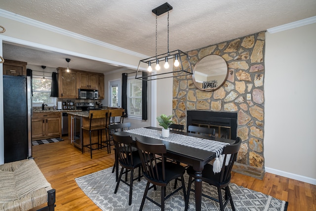 dining area with a textured ceiling, light wood-type flooring, and crown molding