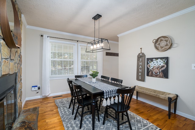 dining space featuring a textured ceiling, wood-type flooring, crown molding, and a chandelier