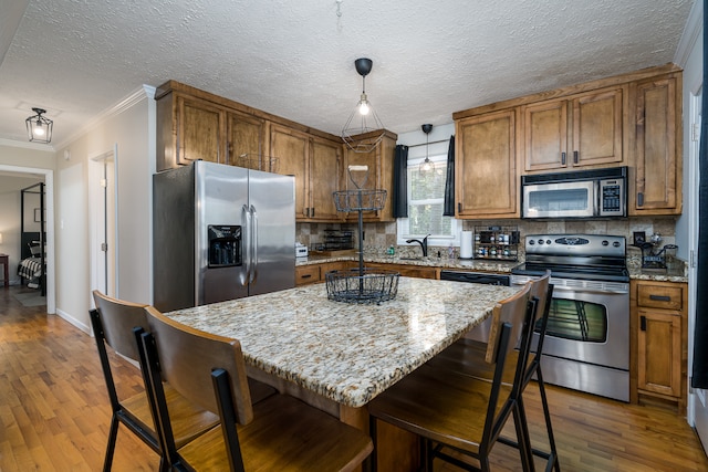 kitchen featuring pendant lighting, ornamental molding, a kitchen island, appliances with stainless steel finishes, and dark hardwood / wood-style flooring