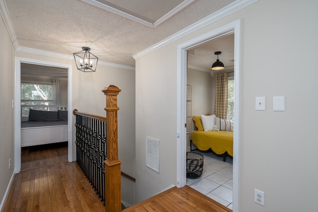 corridor with hardwood / wood-style flooring, ornamental molding, and a textured ceiling