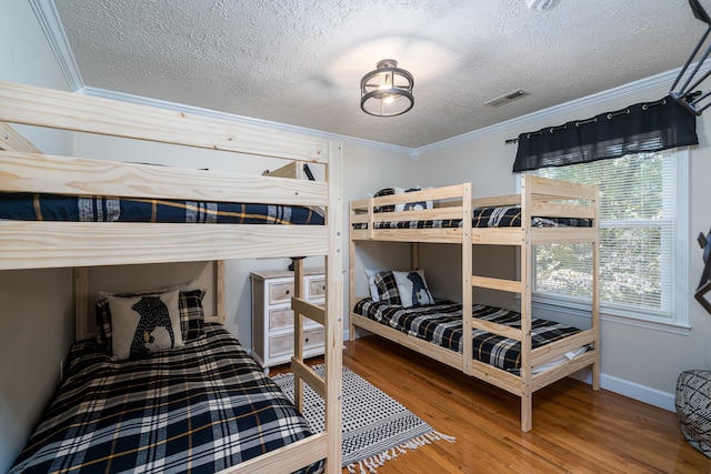 bedroom featuring a textured ceiling, hardwood / wood-style flooring, and crown molding