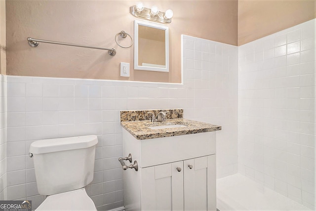 bathroom featuring vanity, tile walls, and toilet