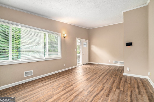 empty room featuring ornamental molding, a textured ceiling, and dark wood-type flooring