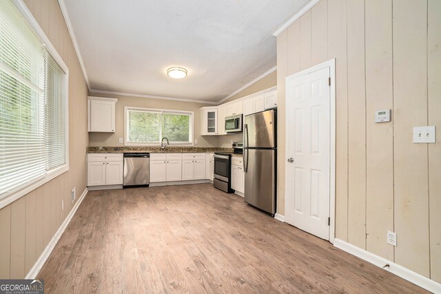 kitchen with ornamental molding, appliances with stainless steel finishes, light hardwood / wood-style floors, and white cabinetry