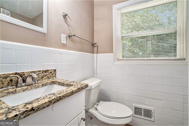 bathroom featuring tile walls, vanity, and toilet