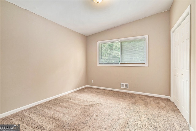 unfurnished bedroom featuring carpet, vaulted ceiling, and a closet