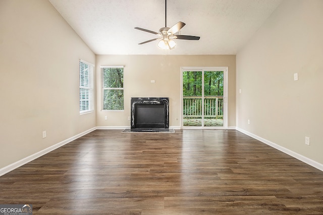 unfurnished living room featuring ceiling fan, a textured ceiling, plenty of natural light, and dark wood-type flooring