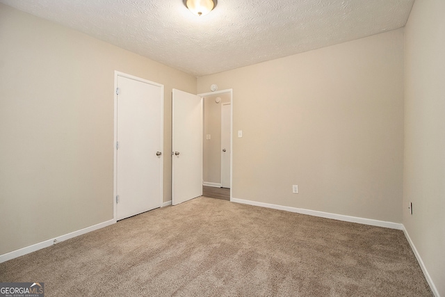 unfurnished room with a textured ceiling and carpet flooring