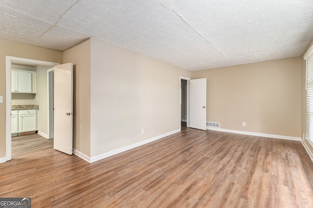 unfurnished room with a textured ceiling and light wood-type flooring