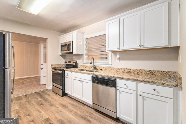 kitchen with appliances with stainless steel finishes, light hardwood / wood-style flooring, white cabinets, and sink