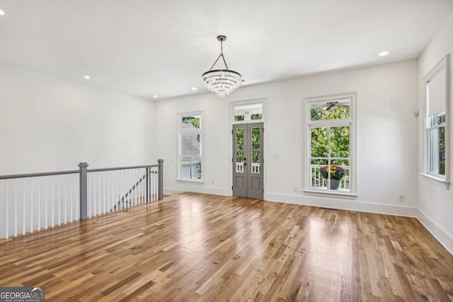 empty room with a notable chandelier and light hardwood / wood-style flooring