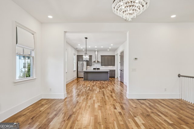 unfurnished living room with an inviting chandelier and light hardwood / wood-style flooring