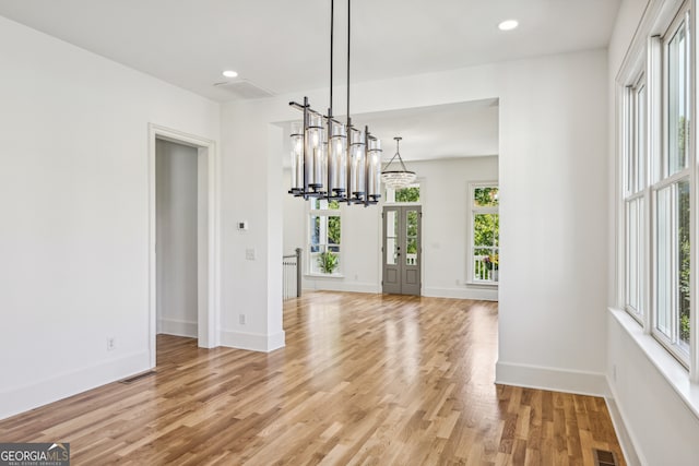 unfurnished dining area featuring light wood-type flooring and a chandelier