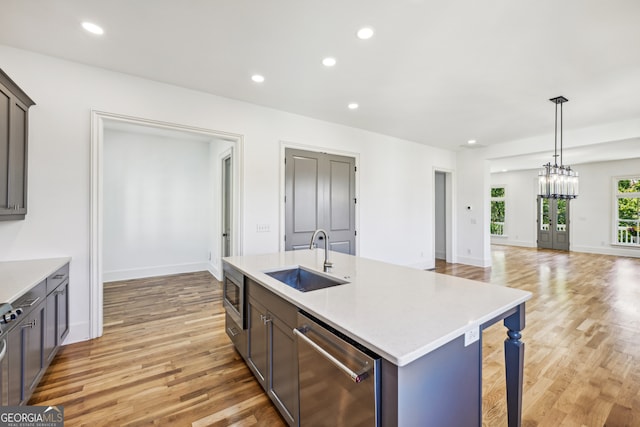 kitchen featuring appliances with stainless steel finishes, sink, light hardwood / wood-style floors, and an island with sink