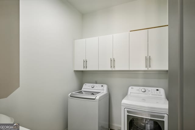 clothes washing area featuring washer and clothes dryer and cabinets