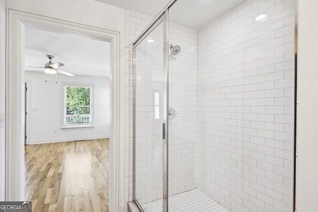 bathroom featuring ceiling fan, a shower with door, and hardwood / wood-style floors