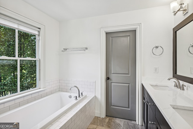 bathroom with a relaxing tiled tub, vanity, and a wealth of natural light