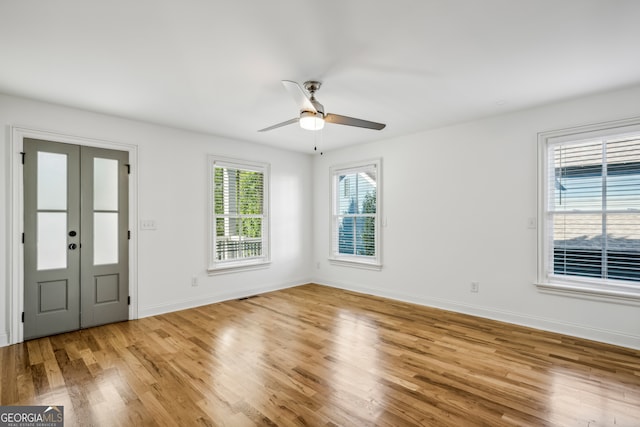 empty room featuring ceiling fan, light wood-type flooring, and french doors