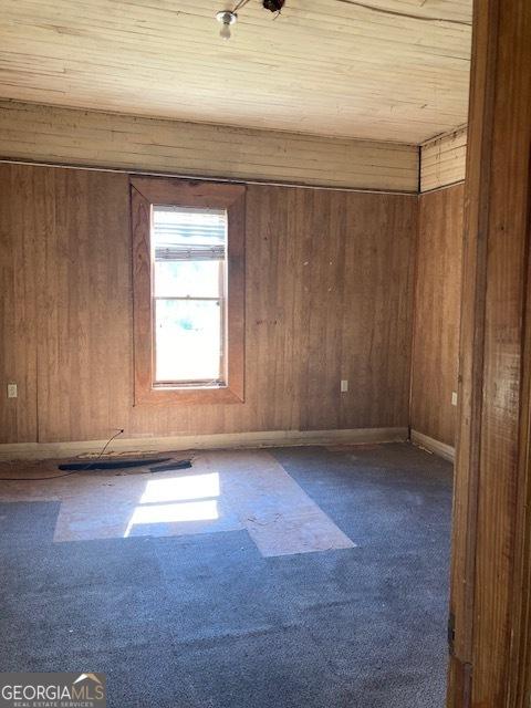 unfurnished room with carpet flooring, wooden ceiling, and wood walls