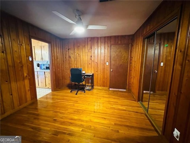 home office with wood walls, ceiling fan, and hardwood / wood-style flooring