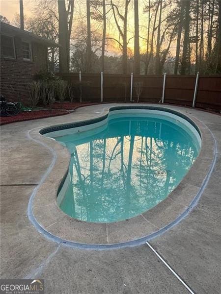 pool at dusk featuring a patio