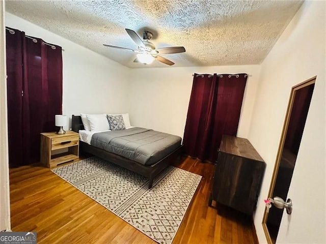 bedroom with ceiling fan, dark hardwood / wood-style floors, and a textured ceiling