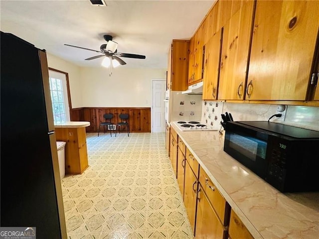 kitchen featuring ceiling fan, wooden walls, tasteful backsplash, and black appliances