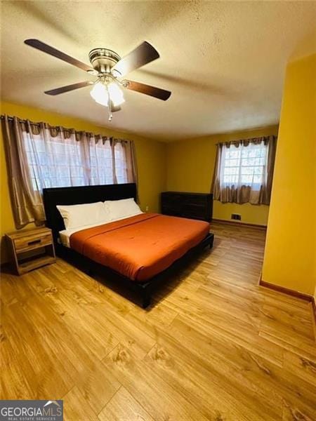 unfurnished bedroom with light hardwood / wood-style floors, ceiling fan, and a textured ceiling