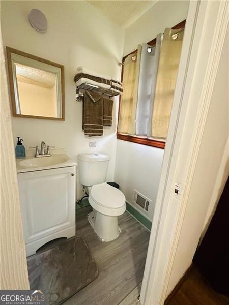 bathroom with hardwood / wood-style floors, vanity, and toilet