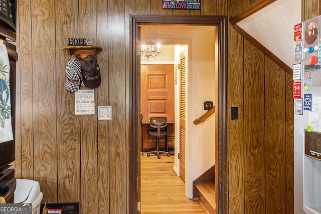 corridor featuring wood walls, hardwood / wood-style flooring, and a textured ceiling