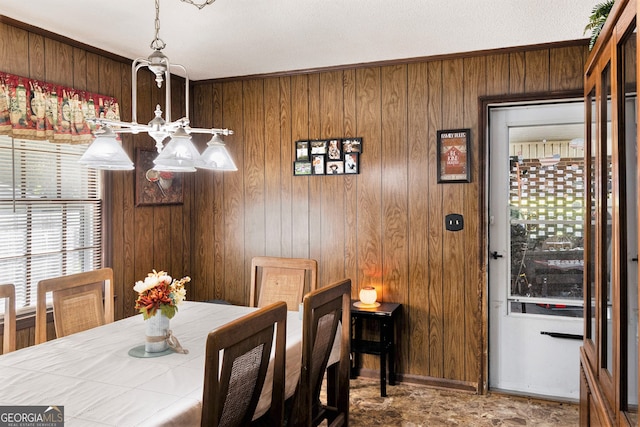 dining space featuring wood walls and an inviting chandelier