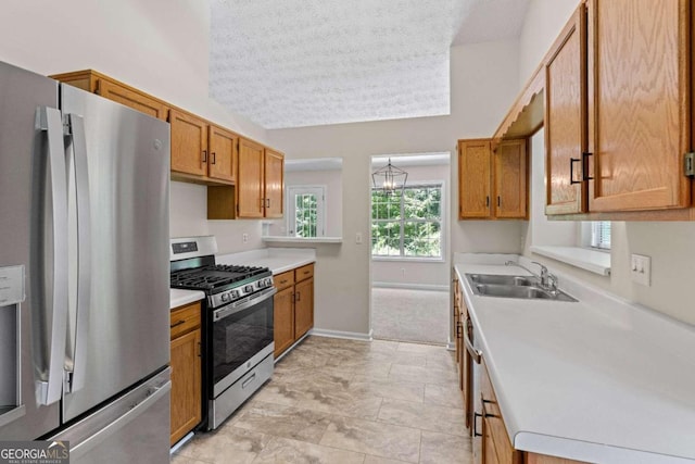 kitchen with vaulted ceiling, a textured ceiling, stainless steel appliances, and sink