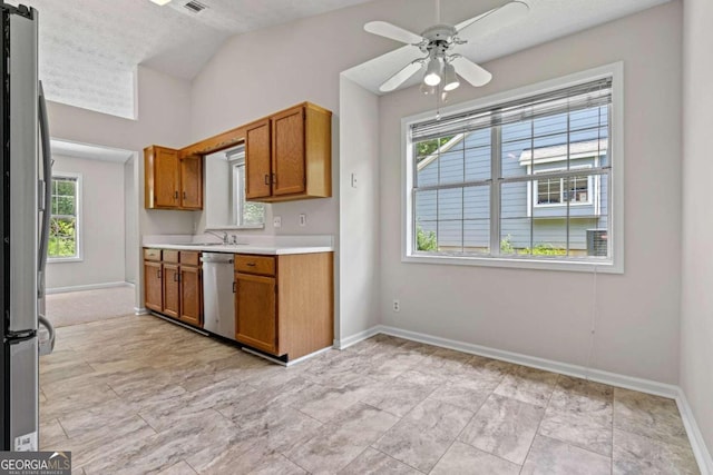 kitchen with stainless steel appliances, vaulted ceiling, a textured ceiling, and plenty of natural light