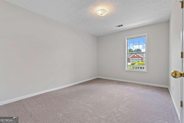 carpeted empty room featuring a textured ceiling