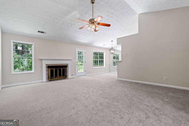 unfurnished living room with a wealth of natural light, carpet, a textured ceiling, and ceiling fan