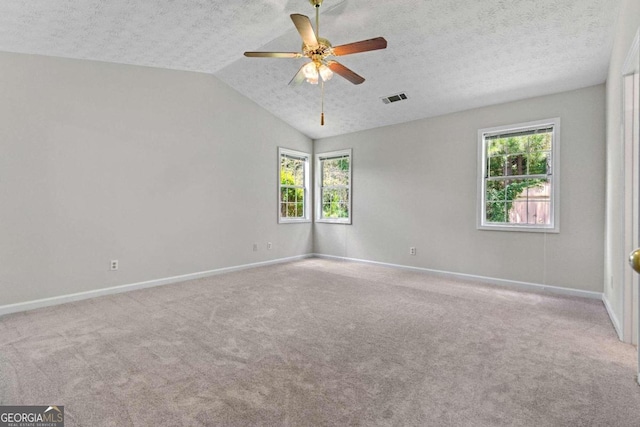 unfurnished room with a textured ceiling, lofted ceiling, ceiling fan, and light carpet